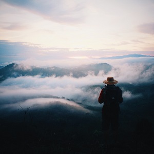 un homme contemple les nuages en haut d'une montagne