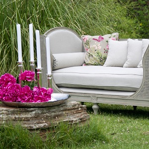 un canapé dans un jardin, avec des bougies et des fleurs en plateau