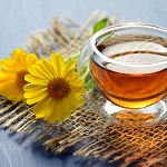 une tasse de tisane transparente avec deux fleurs de calendula